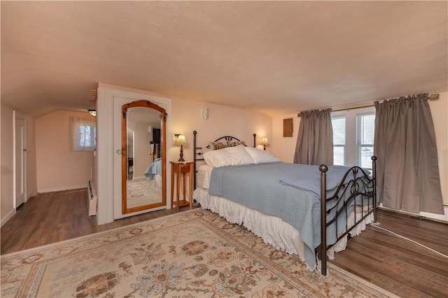 bedroom featuring vaulted ceiling, wood finished floors, and baseboards