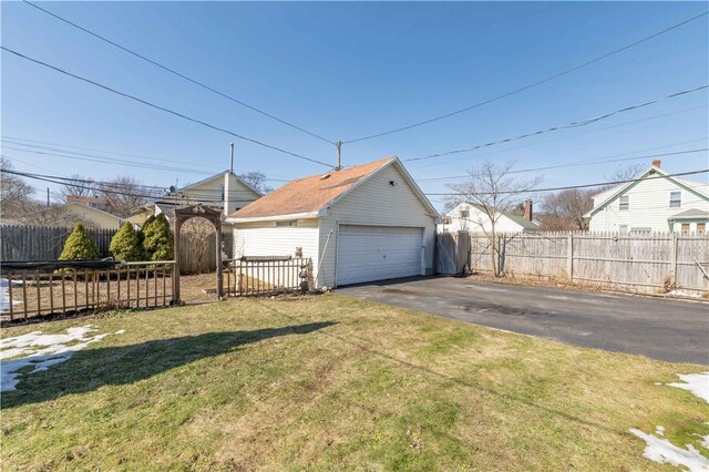 view of side of home featuring an outbuilding, fence, a lawn, and a detached garage