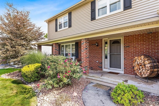 property entrance featuring brick siding and a porch