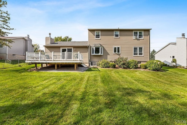 rear view of property with a lawn, a deck, a chimney, and fence