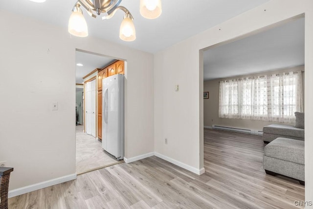 interior space with a notable chandelier, baseboards, baseboard heating, and light wood-style flooring