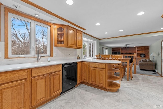 kitchen featuring a sink, tasteful backsplash, black dishwasher, a peninsula, and light countertops