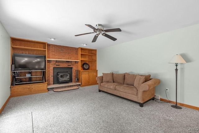 carpeted living area with a wood stove, baseboards, and ceiling fan