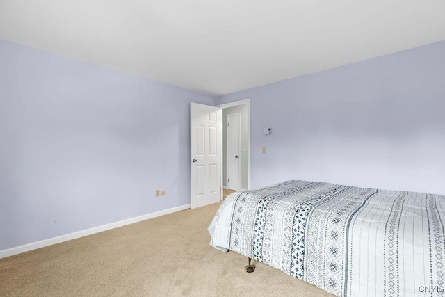 bedroom with light colored carpet and baseboards