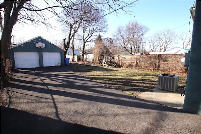 view of yard featuring an outbuilding, fence, central AC unit, and a garage