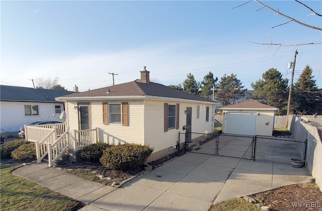 view of front of property with an outbuilding, a gate, fence, concrete driveway, and a chimney