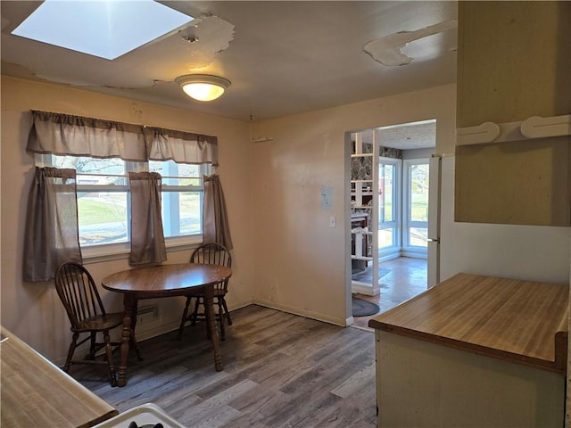 dining area with a skylight, baseboards, and wood finished floors