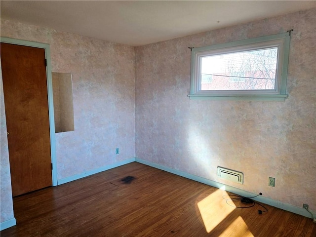 unfurnished room with visible vents, baseboards, and wood finished floors