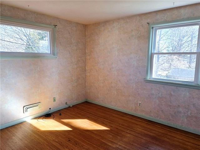 spare room featuring baseboards, a healthy amount of sunlight, and wood finished floors