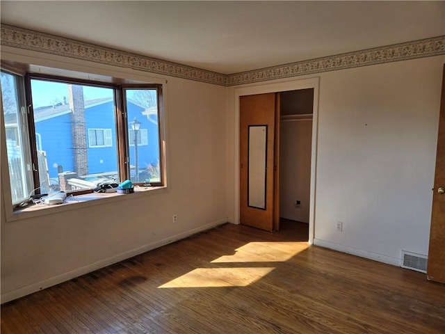 unfurnished bedroom with visible vents, baseboards, a closet, and wood finished floors