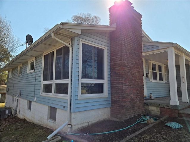 view of property exterior featuring central AC unit, a porch, and a chimney