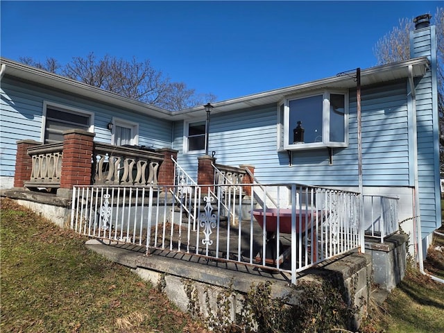 rear view of property featuring a wooden deck and a chimney