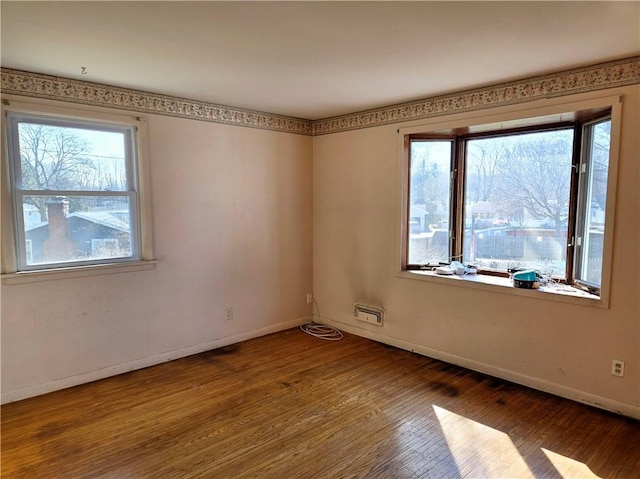 spare room featuring baseboards and wood finished floors