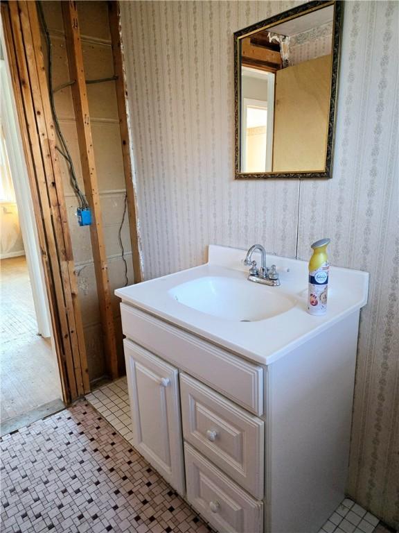 bathroom with wallpapered walls and vanity