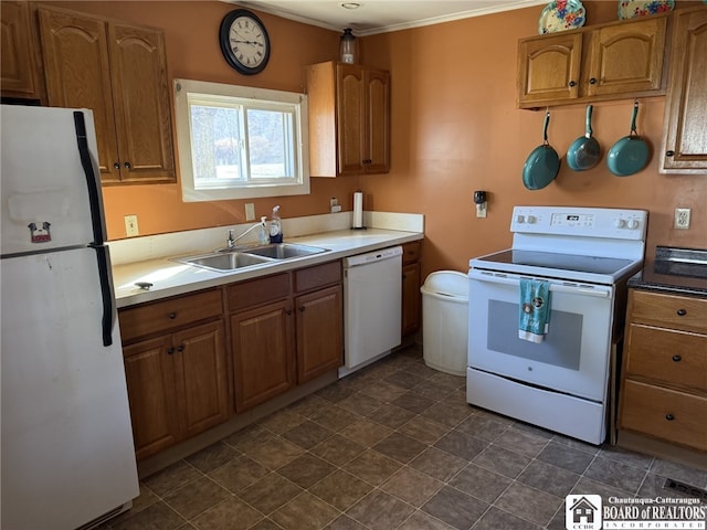 kitchen with white appliances, ornamental molding, brown cabinets, and a sink