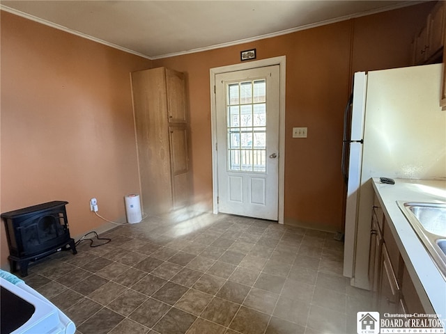 entryway with a sink, a wood stove, and ornamental molding