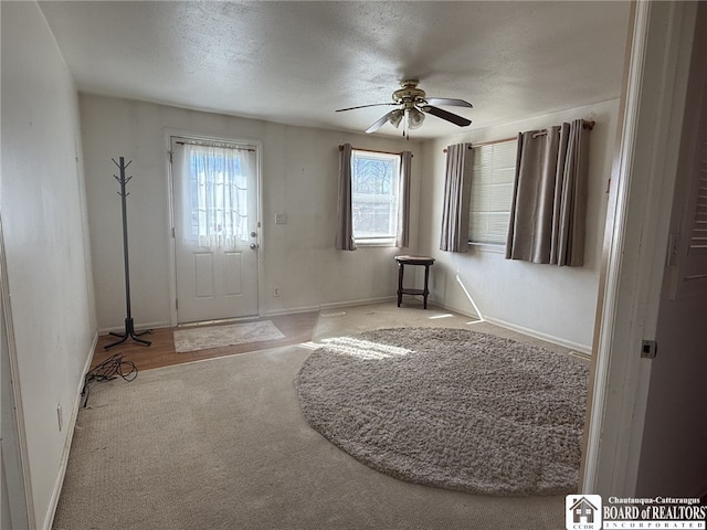 foyer with carpet flooring, ceiling fan, a textured ceiling, and baseboards