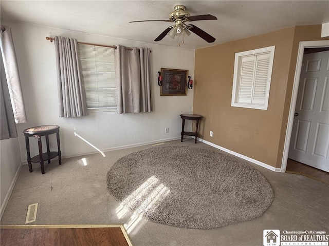 carpeted spare room with visible vents, baseboards, and ceiling fan