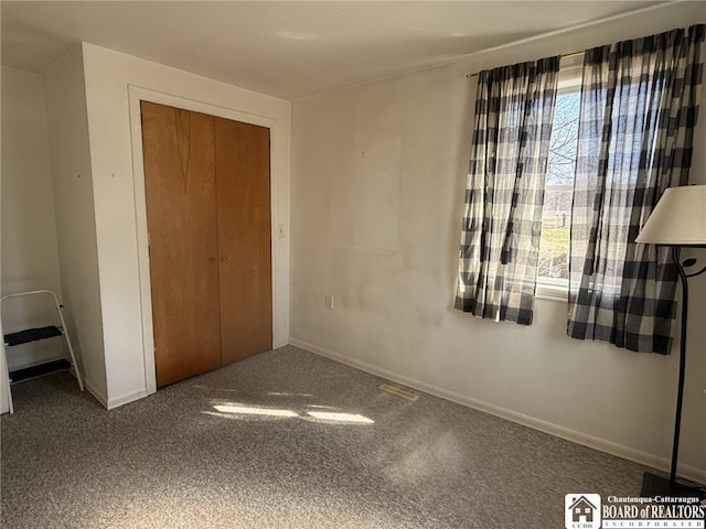 unfurnished bedroom featuring a closet, visible vents, baseboards, and carpet floors