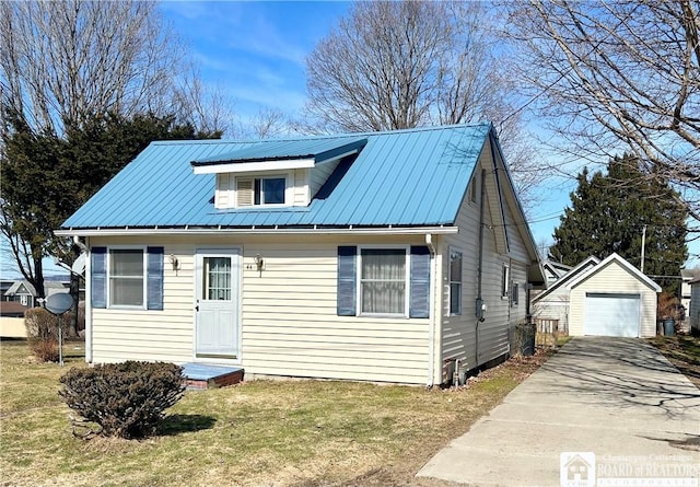 bungalow-style house featuring an outbuilding, a detached garage, concrete driveway, a front yard, and metal roof