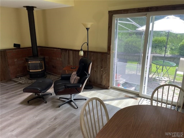 interior space with a wainscoted wall, visible vents, wood finished floors, wood walls, and a wood stove