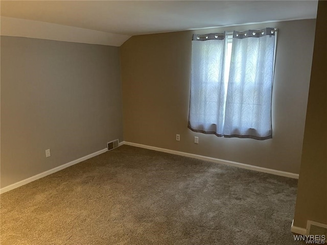 unfurnished room with dark colored carpet, visible vents, lofted ceiling, and baseboards