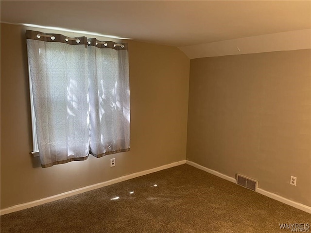 spare room featuring visible vents, carpet flooring, lofted ceiling, and baseboards