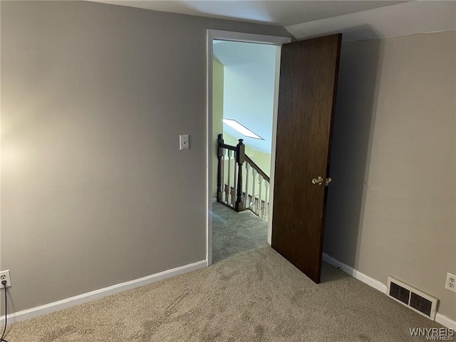 carpeted spare room featuring visible vents and baseboards