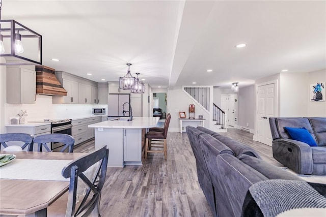 interior space featuring premium range hood, gray cabinetry, light countertops, appliances with stainless steel finishes, and open floor plan