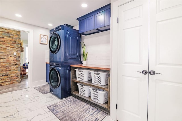 laundry area featuring recessed lighting, cabinet space, marble finish floor, and stacked washer / dryer