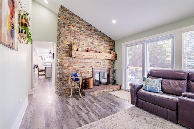 living area featuring a stone fireplace, recessed lighting, baseboards, and wood finished floors