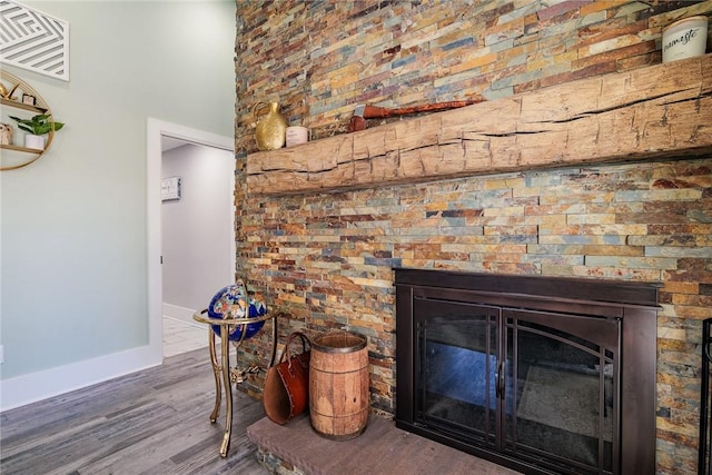 room details with visible vents, wood finished floors, baseboards, and a glass covered fireplace