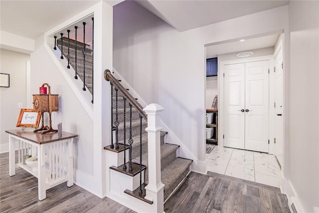 staircase featuring marble finish floor and baseboards