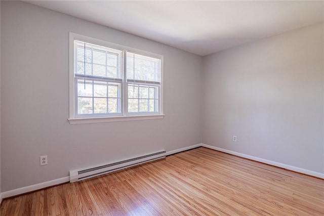 empty room with a baseboard heating unit, baseboards, and light wood finished floors