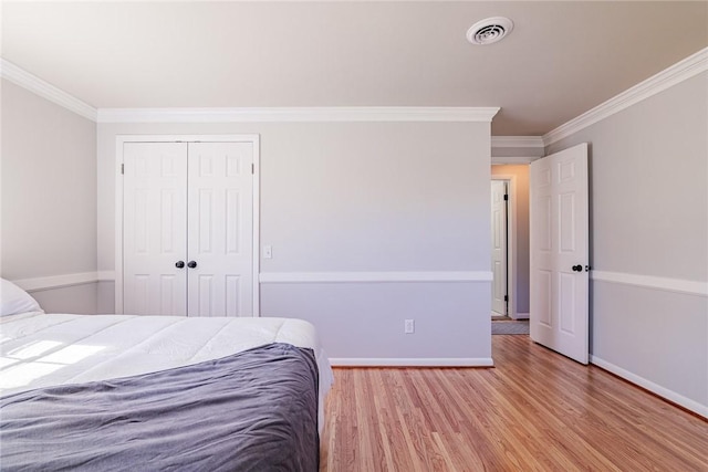 unfurnished bedroom featuring a closet, visible vents, crown molding, and wood finished floors