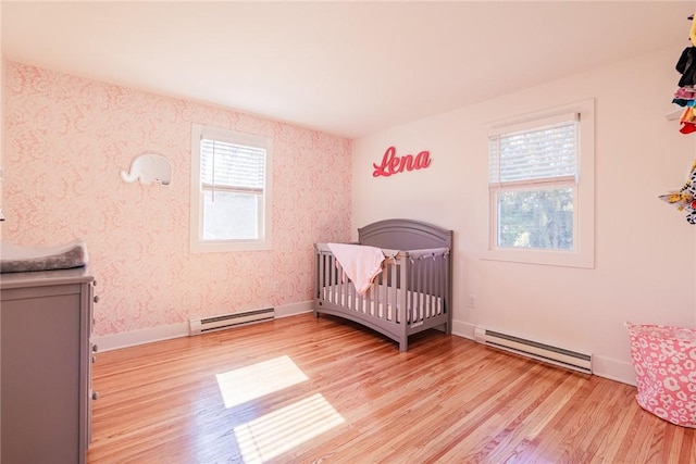 bedroom with light wood finished floors, baseboard heating, and baseboards