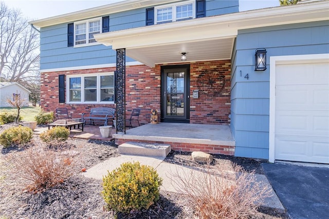 view of exterior entry featuring brick siding, covered porch, and an attached garage