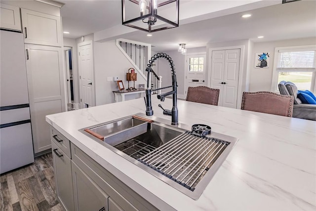 kitchen with dark wood-type flooring, a sink, light stone counters, open floor plan, and recessed lighting