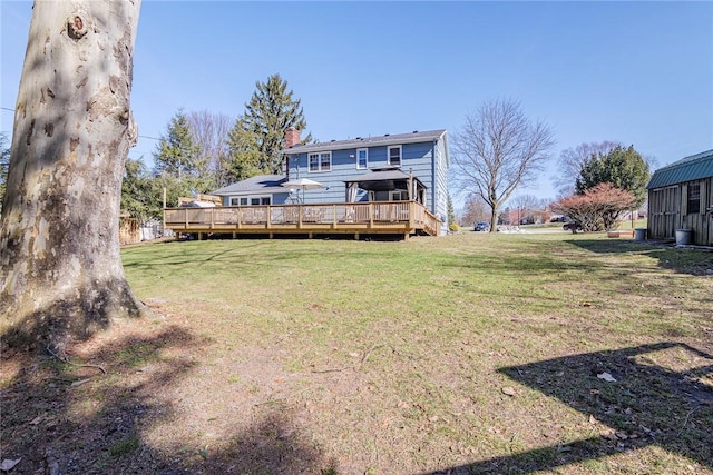 rear view of property featuring a yard, a chimney, and a wooden deck