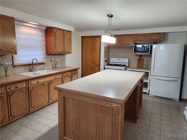 kitchen with brown cabinetry, white appliances, a kitchen island, and a sink