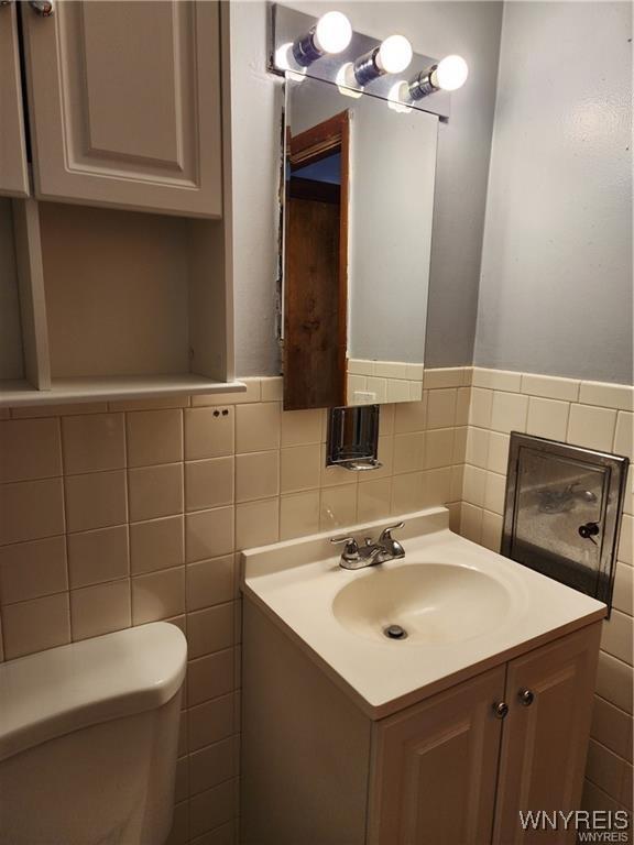 bathroom featuring vanity, tile walls, and toilet