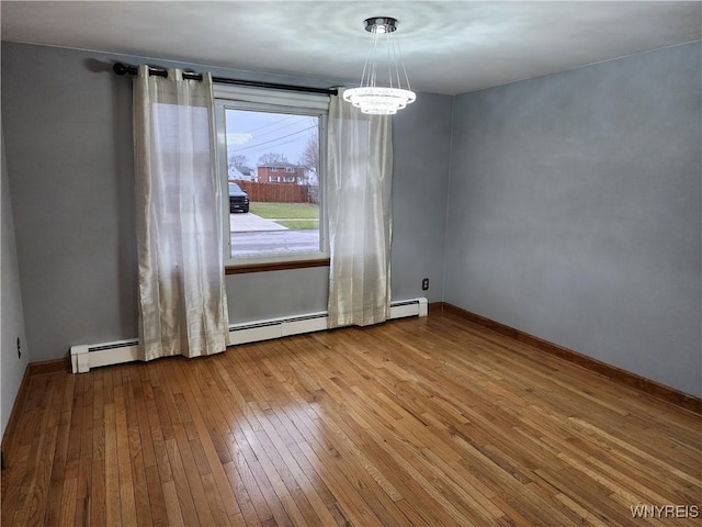 unfurnished dining area with a notable chandelier, baseboard heating, baseboards, and hardwood / wood-style floors