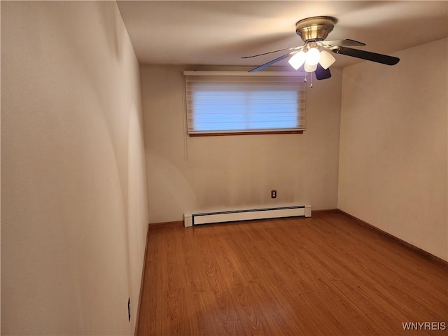 empty room featuring baseboards, a baseboard heating unit, a ceiling fan, and wood finished floors