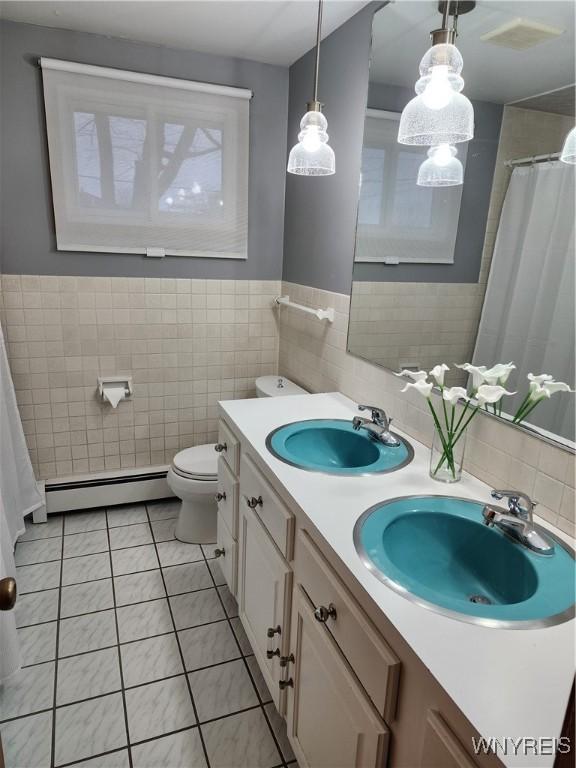 full bath with a sink, baseboard heating, tile patterned floors, and toilet