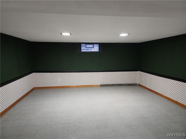 below grade area featuring tile patterned floors, a wainscoted wall, wallpapered walls, and baseboards