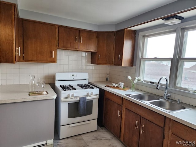 kitchen featuring white gas stove, marble finish floor, light countertops, and a sink