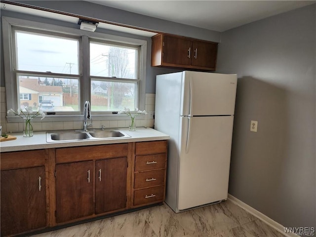 kitchen featuring a sink, marble finish floor, light countertops, and freestanding refrigerator