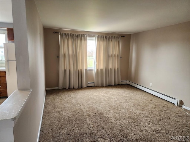 empty room featuring a wealth of natural light, carpet, and baseboard heating