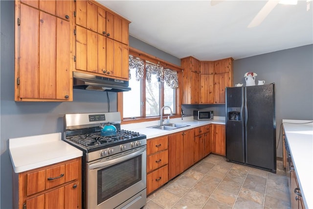 kitchen with under cabinet range hood, light countertops, brown cabinetry, stainless steel appliances, and a sink