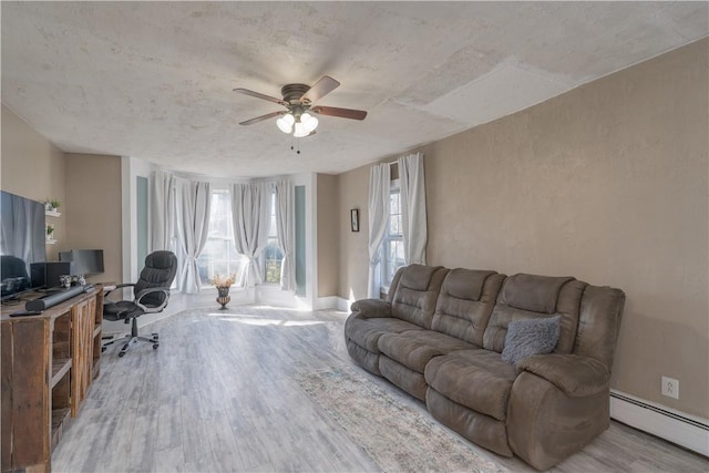 living area with baseboard heating, a ceiling fan, and wood finished floors